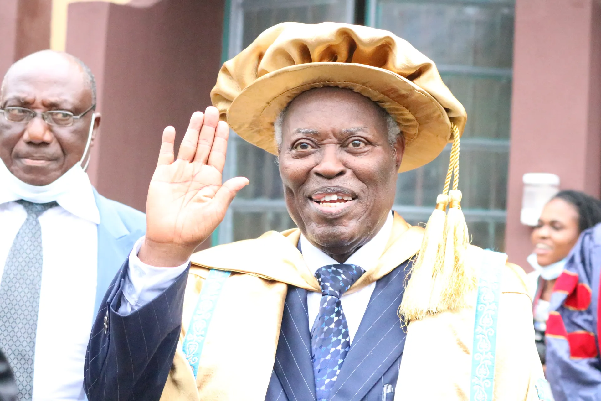Chancellor waving while wearing academic regalia