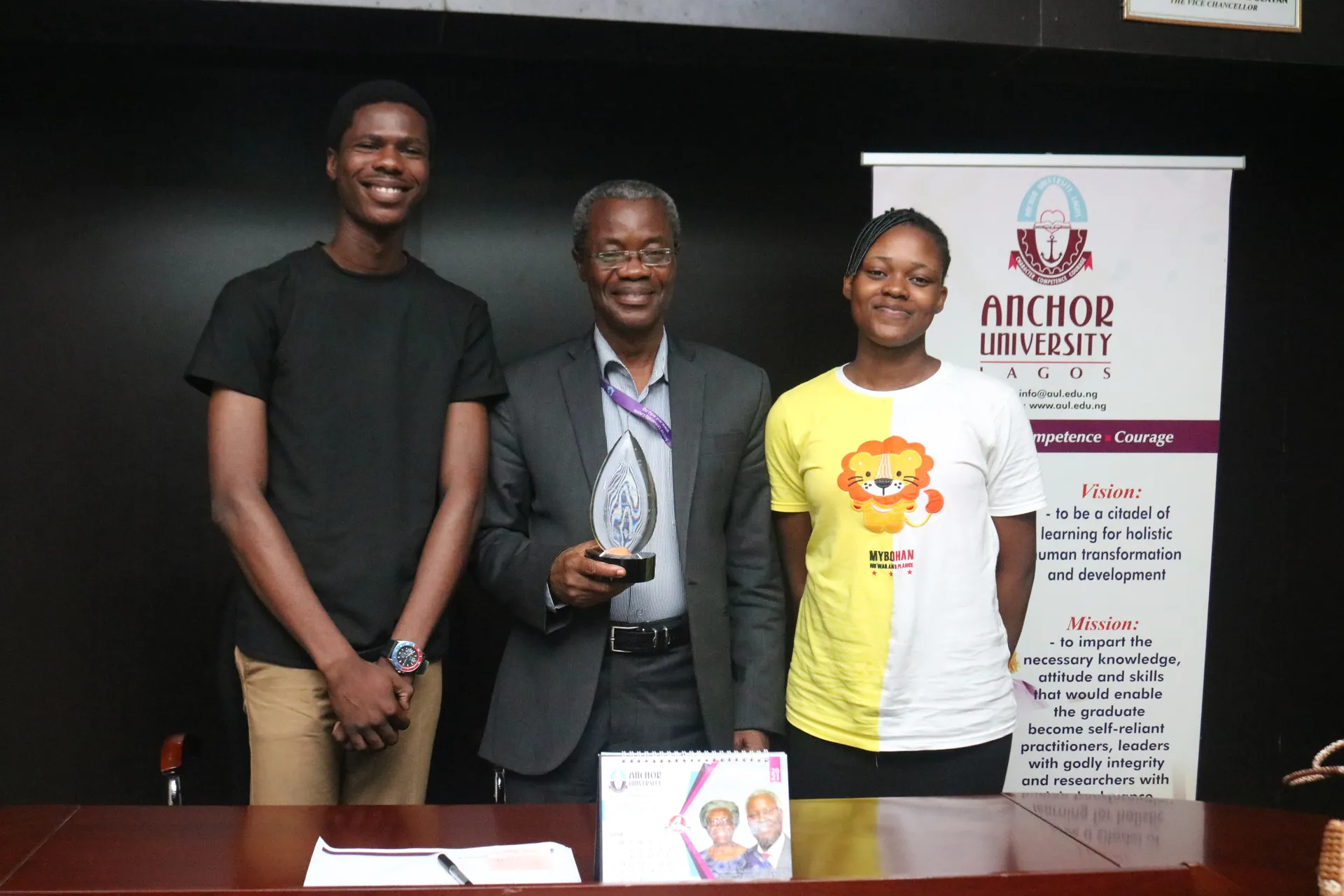 Students displaying an award with a university representative