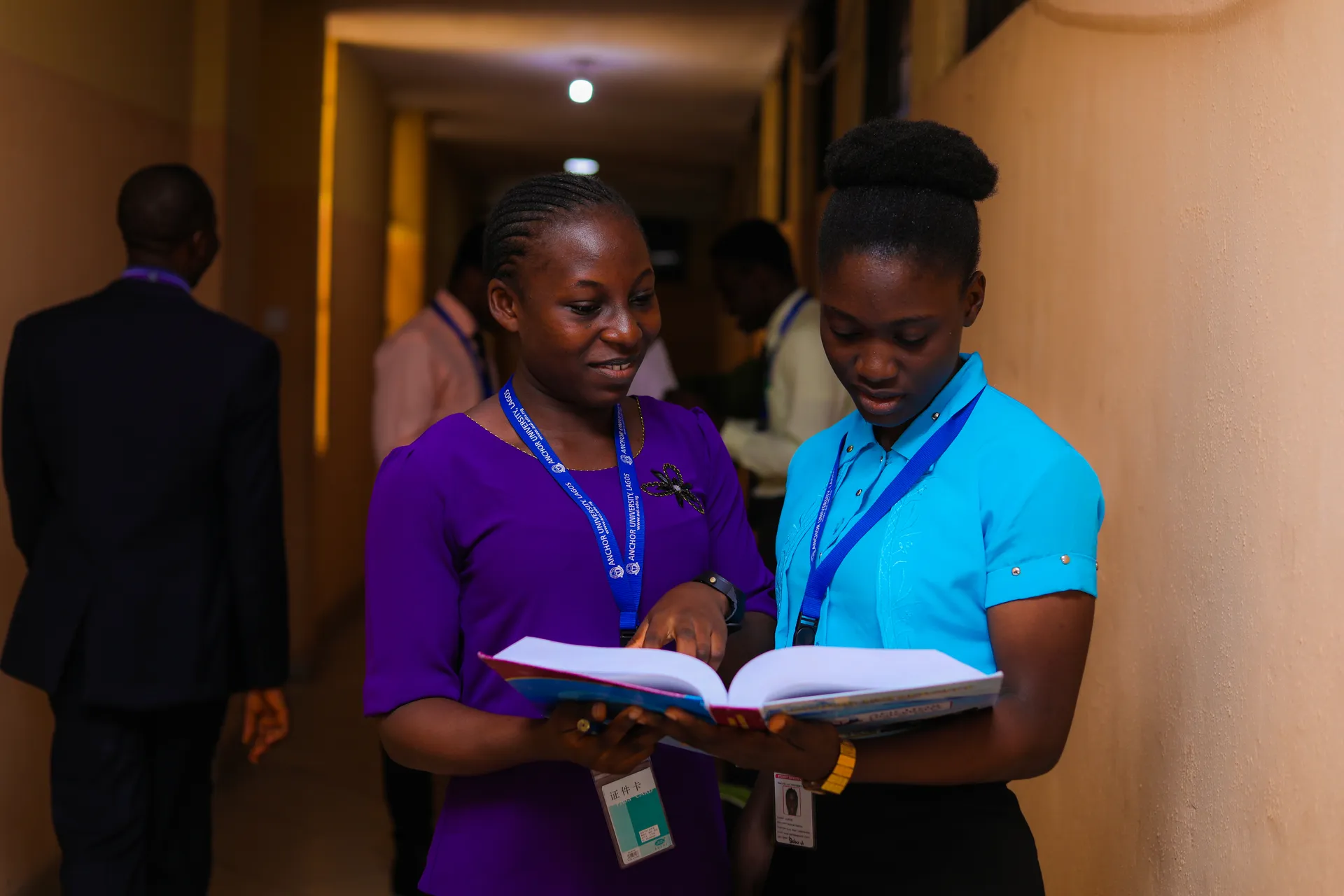 Two students reading together in a corridor
